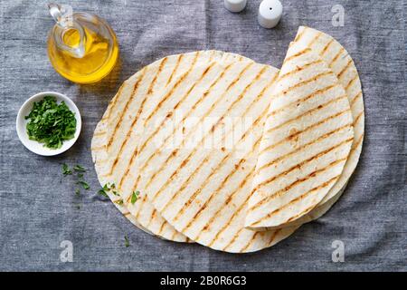 Tortillas, flat breads on grey textile background. Copy space. Top view. Stock Photo