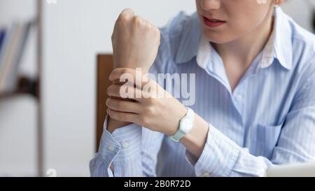 Close up unhappy businesswoman holding writs, suffering from carpal tunnel syndrome, feeling pain after long computer work, using mouse and typing on Stock Photo