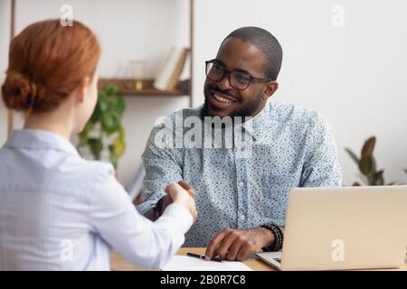 Smiling African American hr manager shaking hand of candidate at job interview, hiring, greeting, good first impression concept, successful negotiatio Stock Photo