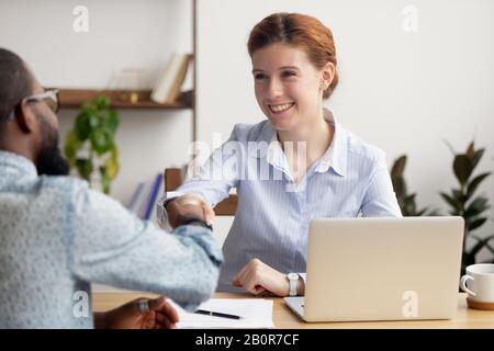 Smiling hr manager shaking hand of African American job applicant, greeting, good first impression concept, successful interview, agreement, friendly Stock Photo