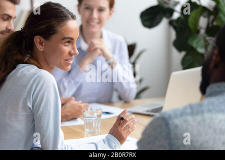 Diverse colleagues discussing project in boardroom at company meeting, mixed race businesswoman talking, sharing thoughts, having pleasant conversatio Stock Photo