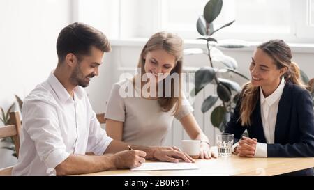 Smiling businessman signing contract, making legal deal with business partners, new team member putting signature on job agreement, satisfied client t Stock Photo