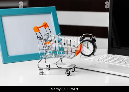 shopping online concept. small toy trolley and gadgets on the table Stock Photo