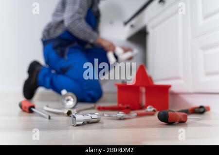 Male Plumber In Overall Fixing Kitchen Sink Pipe Stock Photo