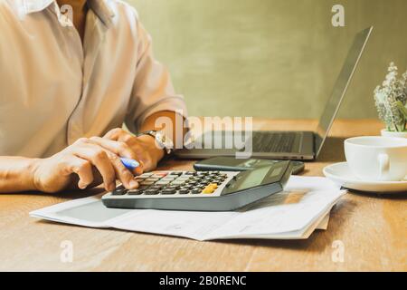 Businessman analyzing investment charts using calculator for calculate profit and loss Stock Photo