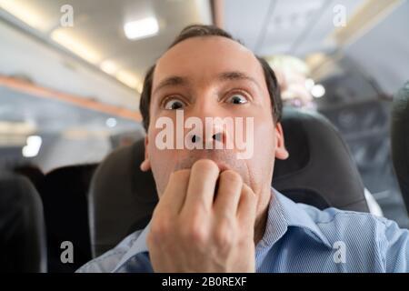 Young Man Having Anxiety Attack In Airplane Stock Photo