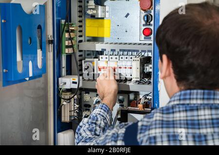 Photo Of Young Male Technician Examining Fusebox Stock Photo