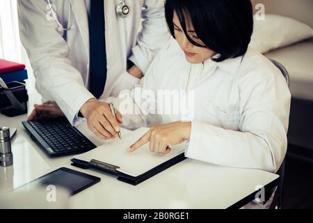 Two Doctors discussing about patient report in ward at hospital. Stock Photo