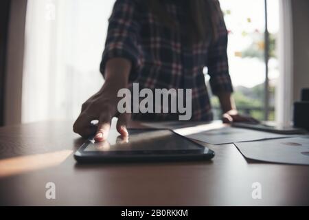 Female hand touching tablet display on table. Stock Photo