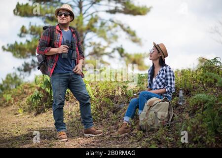 Thoughtful hiking couple looking away while relaxing in forest Stock Photo