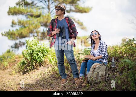 Thoughtful hiking couple looking away while relaxing in forest Stock Photo
