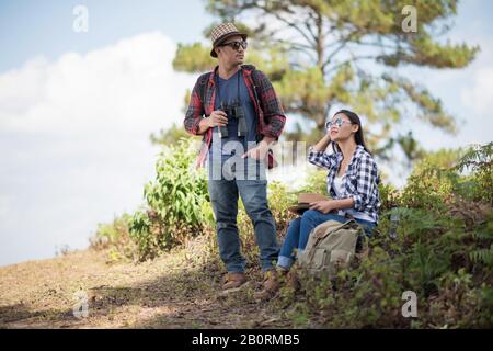 Thoughtful hiking couple looking away while relaxing in forest Stock Photo
