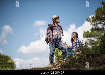Thoughtful hiking couple looking away while relaxing in forest Stock Photo