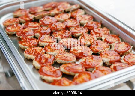 An upper view on the metal container full of hamburger patties with ketchup sauce Stock Photo