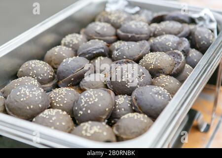 A closeup view of exotic black colored mini hamburger buns in metal container Stock Photo