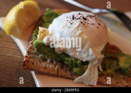 Poached egg with pepper on guacamole with toast and a wedge of lemon Stock Photo