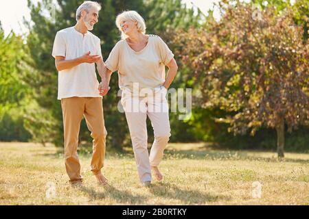 Happy couple of seniors taking a walk in nature in summer Stock Photo