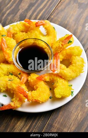 Deep fried breaded shrimp with sauce on plate on wooden table. Stock Photo