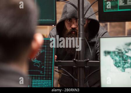Shot of dangerous cyber criminals hacking credit cards from computer with multiple screens. Stock Photo