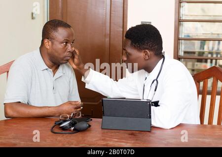 Medicine consults his patient sitting in front of him in his clinic while watching in his eye Stock Photo