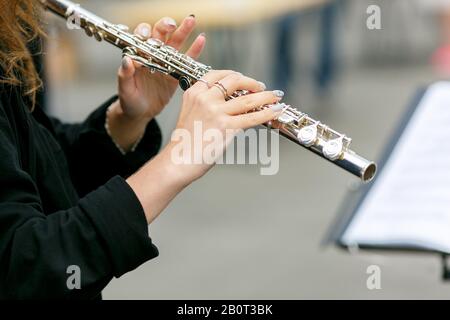 A closeup plane of street orchestra flautist with flute in her hands Stock Photo