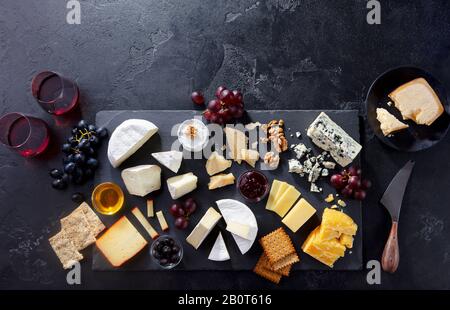 Cheese assortment on slate cutting board with wine. Grey background. Top view. Copy space. Stock Photo