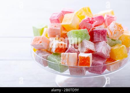 Assortment of Turkish delights on a glass stand. White wooden background. Close up. Stock Photo