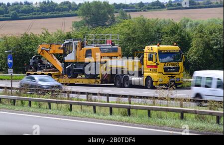 low loader lorry carrying heavy giant digger on trailer travelling on ...