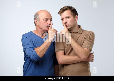 Handsome two men father and son making silence gesture. studio shot Stock Photo