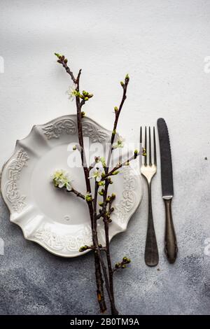 Spring table setting with cutlery and blooming cherry branch on rustic background with copy space Stock Photo