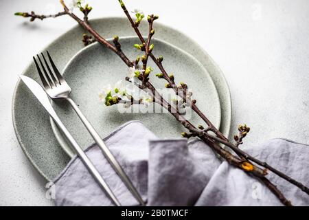 Spring table setting with cutlery and blooming cherry branch on rustic background with copy space Stock Photo