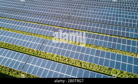 Solar Farm and panels. Rows of solar panels creating an abstract full-frame background texture of blue and green on a bright sunny day. Stock Photo