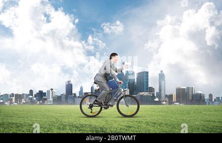 Businessman with megaphone on bike Stock Photo