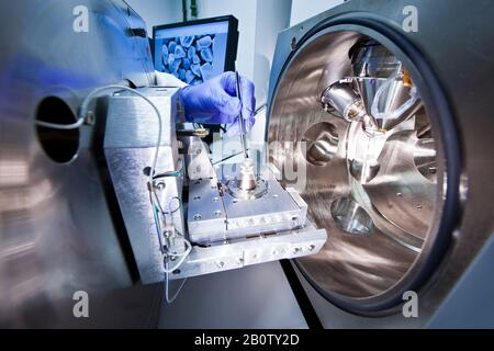 A scientist with tweezers in his hand using scanning electronic microscope Stock Photo