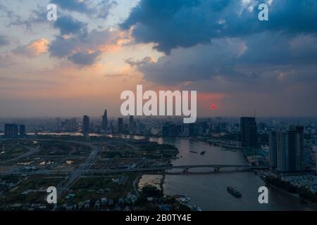 Dramatic aerial view of Saigon river and Ho Chi Minh City skyline at sunset with beautiful stormy and brightly colored clouds in the sky Stock Photo