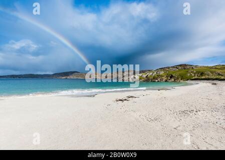 Rainbow over remote empty Achmelvich beach on the shore of Achmelvich Bay in Assynt, Sutherland in the North West Scottish Highlands Stock Photo
