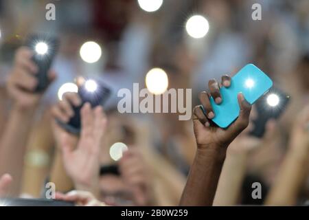 Person holding a cellphone with the flash on and hands up Stock Photo
