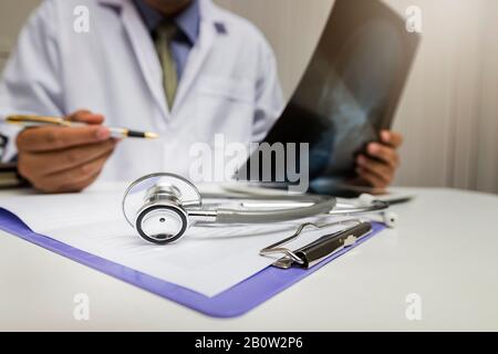Medicine and health care concept. Close-up of stethoscope is lying on the clipboard near a doctor consults patient. Stock Photo