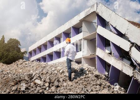 Engineer holding tablet is checking for destruction, demolishing building. Stock Photo