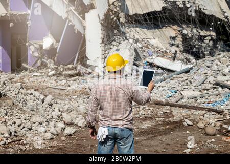 Engineer holding tablet is checking for destruction, demolishing building. Stock Photo
