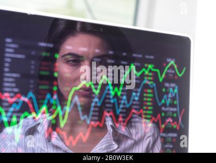Female analyst viewing financial market data on a screen. Stock Photo