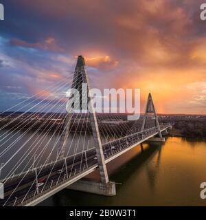 Budapest, Hungary - Aerial view of Megyeri Bridge over River Danube with beautiful golden sky and clouds and heavy traffic at sunset Stock Photo