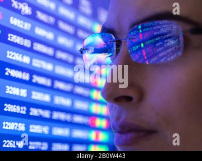 Female analyst viewing financial market data on a screen. Stock Photo