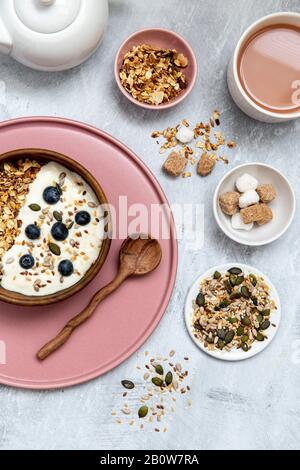 Bowl of muesli and blueberries on yogurt, assortment of seeds, brown and white sugar cubes Stock Photo