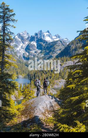 Hikers enjoying view on rock, Alpine Lakes Wilderness, Washington, USA Stock Photo