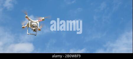 Drone with digital camera flying in the sky. Modern technology for aerial video and photography. Stock Photo