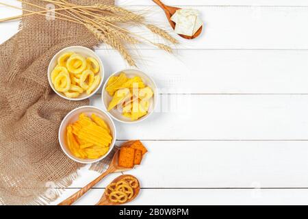 Mix of snacks : pretzels , crackers , chips and nachos on the table Stock Photo