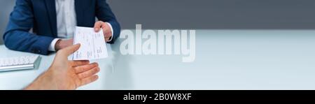 Close-up Of A Business Man Giving Cheque To His Colleague At Workplace In Office Stock Photo