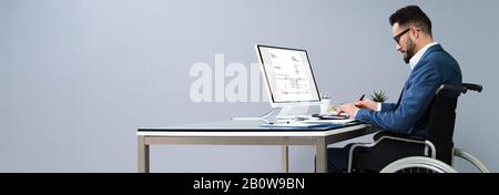 Businessman Sitting On Wheelchair And Using Computer Stock Photo