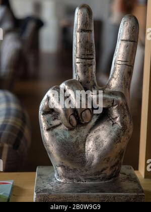 Close-up photo of a metal figurine in the form of a hand with two fingers raised up Stock Photo